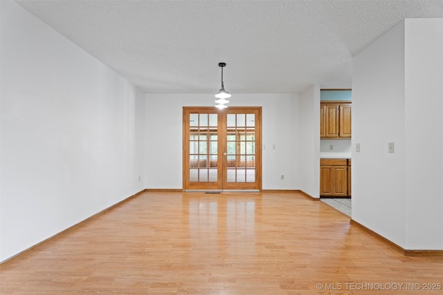 1558 E N Ridge Dr, Vinita, OK 74301 - unfurnished dining area with light wood finished floors, french doors, baseboards, and a textured ceiling