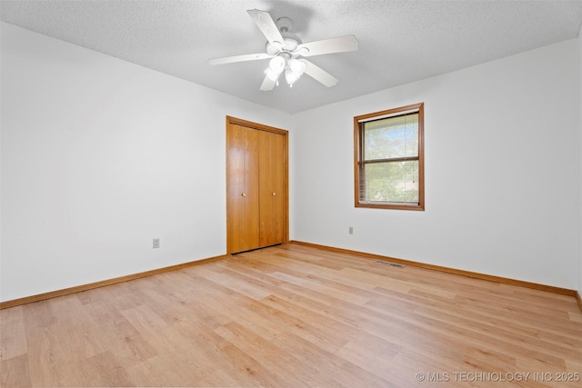 1558 E N Ridge Dr, Vinita, OK 74301 - unfurnished bedroom with light wood-style floors, baseboards, a closet, and a textured ceiling