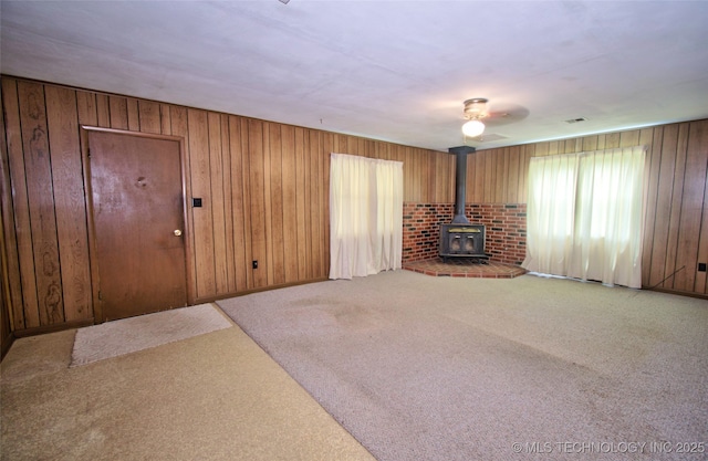 4120 W 53rd St S, Muskogee, OK 74401 - unfurnished living room with a wood stove, carpet floors, wood walls, and a ceiling fan