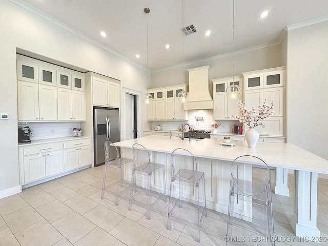 20115 W 111th St S, Sapulpa, OK 74066 - kitchen featuring stainless steel refrigerator with ice dispenser, custom range hood, a kitchen bar, tasteful backsplash, and ornamental molding