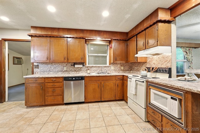 73645 Cyclone Cir, Wagoner, OK 74467 - kitchen featuring white appliances, under cabinet range hood, brown cabinets, a sink, and backsplash