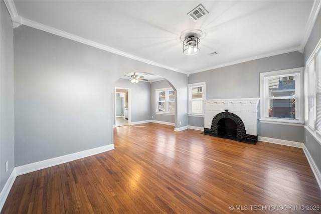 1232 S Gary Pl, Tulsa, OK 74104 - unfurnished living room featuring arched walkways, plenty of natural light, a fireplace, wood finished floors, and crown molding