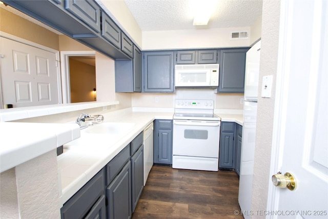 6737 S Peoria Ave Unit C213, Tulsa, OK 74136 - kitchen with white appliances, dark wood-type flooring, a textured ceiling, a sink, and tile counters
