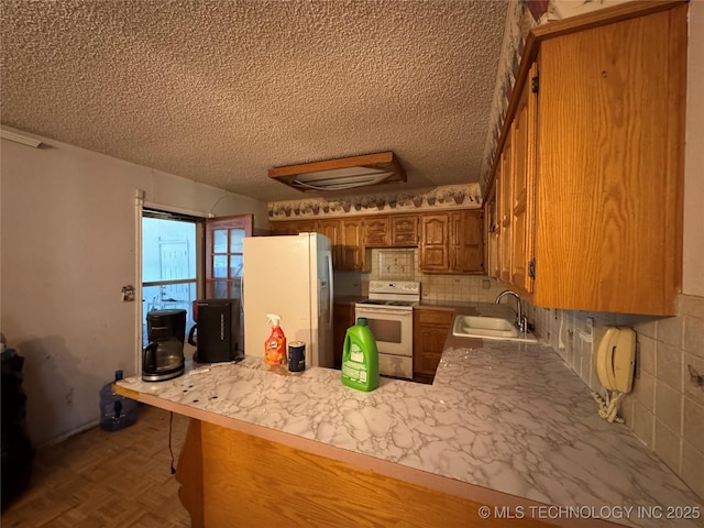 10653 E 18th St, Tulsa, OK 74128 - kitchen featuring white appliances, a sink, a textured ceiling, brown cabinetry, and a peninsula