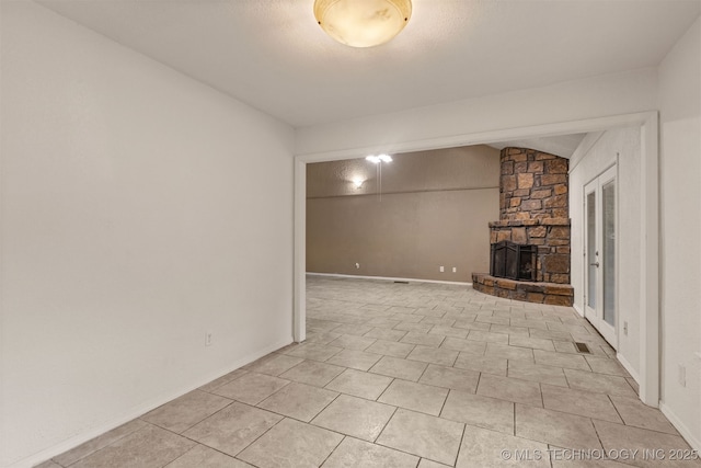 8424 Harp Blvd, Broken Arrow, OK 74014 - unfurnished living room featuring a stone fireplace, vaulted ceiling, and light tile patterned flooring
