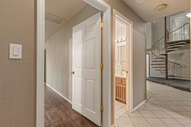 8424 Harp Blvd, Broken Arrow, OK 74014 - hallway with a textured wall, stairway, baseboards, tile patterned flooring, and a textured ceiling