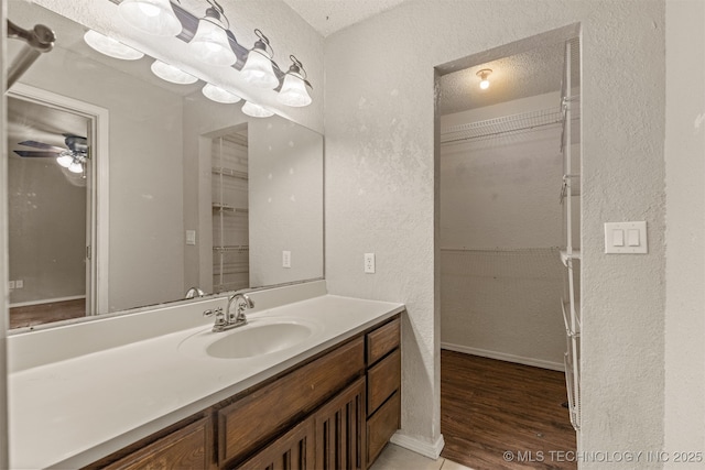 8424 Harp Blvd, Broken Arrow, OK 74014 - bathroom with a textured wall, vanity, a walk in closet, wood finished floors, and ceiling fan
