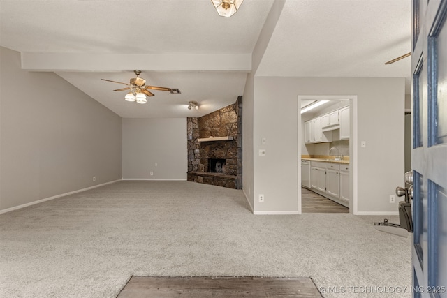 4012 S Cedar Ave, Broken Arrow, OK 74011 - unfurnished living room featuring a stone fireplace, carpet flooring, a ceiling fan, a sink, and baseboards