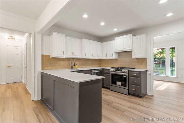 7802 S Joplin Ave, Tulsa, OK 74136 - kitchen with appliances with stainless steel finishes, a sink, white cabinetry, a peninsula, and light wood-style floors