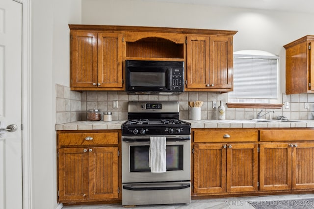 12326 S Cedar Ave, Jenks, OK 74037 - kitchen featuring black microwave, stainless steel range with gas stovetop, tasteful backsplash, brown cabinetry, and tile counters