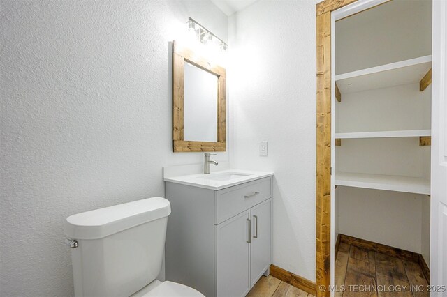 984 Ridgepoint, Fort Towson, OK 74735 - bathroom featuring wood finished floors, vanity, toilet, and a textured wall