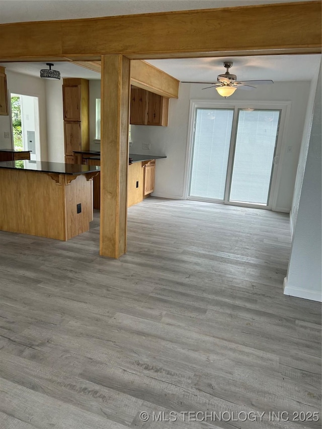 4613 N Main St E, Tulsa, OK 74115 - kitchen with dark countertops, light wood-type flooring, a kitchen breakfast bar, beamed ceiling, and ceiling fan