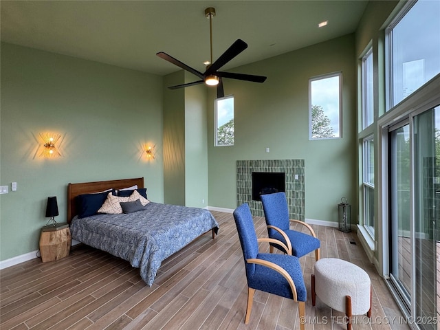 659 Sleepy Hollow Ln, Cleveland, OK 74020 - bedroom with multiple windows, wood finished floors, a tile fireplace, baseboards, and a high ceiling