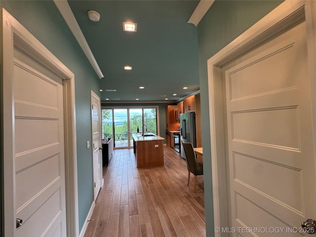 659 Sleepy Hollow Ln, Cleveland, OK 74020 - kitchen with high end fridge, light wood finished floors, an island with sink, light countertops, and baseboards