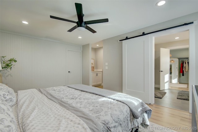 5132 S Atlanta Ave, Tulsa, OK 74105 - bedroom featuring a barn door, light wood-type flooring, recessed lighting, ceiling fan, and ensuite bathroom