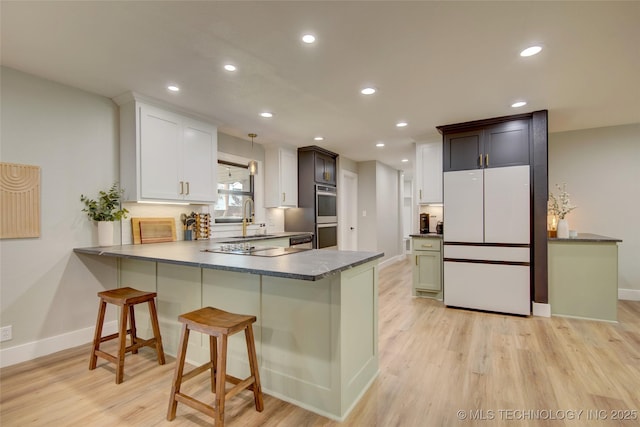 5132 S Atlanta Ave, Tulsa, OK 74105 - kitchen with freestanding refrigerator, baseboards, a peninsula, light wood-type flooring, and recessed lighting