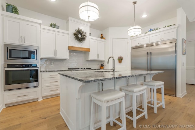 1228 W 85th Ct S, Tulsa, OK 74132 - kitchen featuring built in appliances, a sink, light wood-style flooring, tasteful backsplash, and recessed lighting