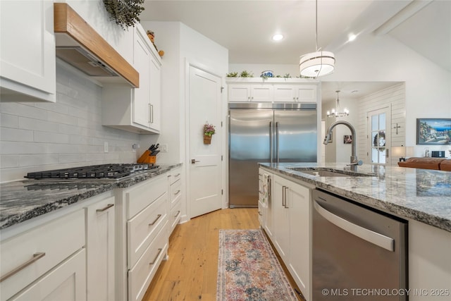 1228 W 85th Ct S, Tulsa, OK 74132 - kitchen with appliances with stainless steel finishes, premium range hood, white cabinets, light wood-style floors, and decorative backsplash