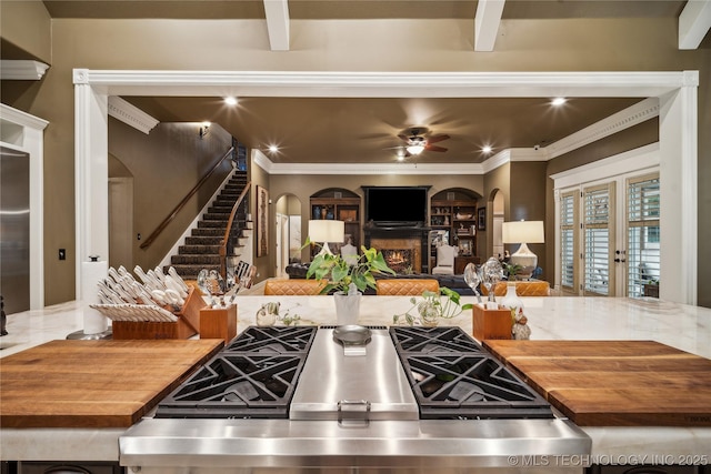 6317 E 110th St, Tulsa, OK 74137 - kitchen with wooden counters, arched walkways, a lit fireplace, a ceiling fan, and ornamental molding