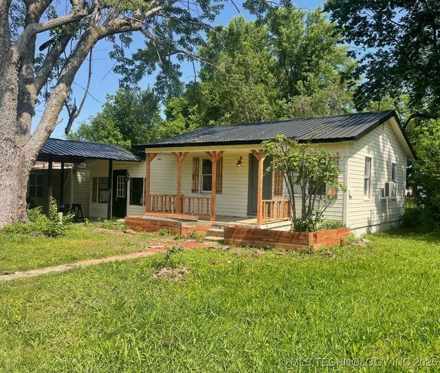 7 E Locust St, Stilwell, OK 74960 - single story home with a porch, a front lawn, metal roof, and cooling unit