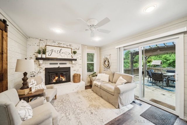 719 W Teel Rd, Sapulpa, OK 74066 - living room with a ceiling fan, wood finished floors, a glass covered fireplace, and wooden walls
