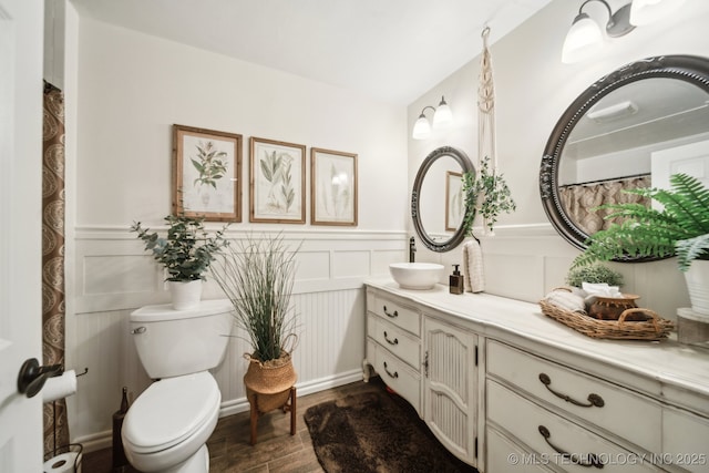 719 W Teel Rd, Sapulpa, OK 74066 - bathroom featuring a decorative wall, wood finished floors, vanity, a wainscoted wall, and toilet