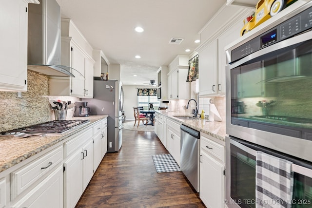 805 E 10th St, Claremore, OK 74017 - kitchen featuring wall chimney range hood, appliances with stainless steel finishes, a sink, white cabinets, and recessed lighting