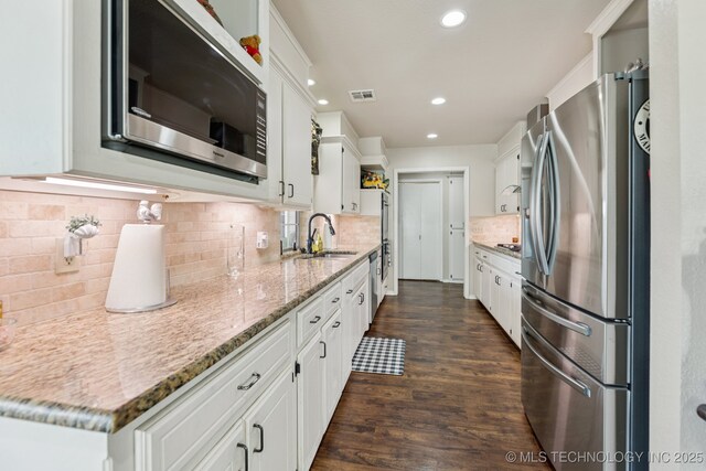 805 E 10th St, Claremore, OK 74017 - kitchen featuring appliances with stainless steel finishes, a sink, white cabinetry, dark wood-style flooring, and recessed lighting