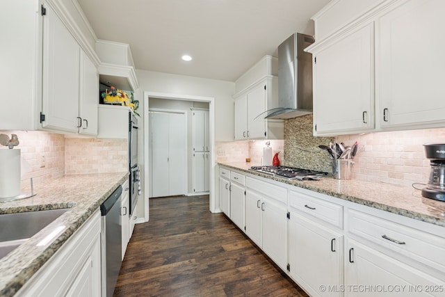 805 E 10th St, Claremore, OK 74017 - kitchen with wall chimney range hood, appliances with stainless steel finishes, white cabinetry, dark wood-style floors, and backsplash