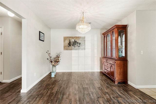 1309 N Willow Ave, Broken Arrow, OK 74012 - unfurnished dining area with a chandelier, dark wood finished floors, baseboards, and a textured ceiling