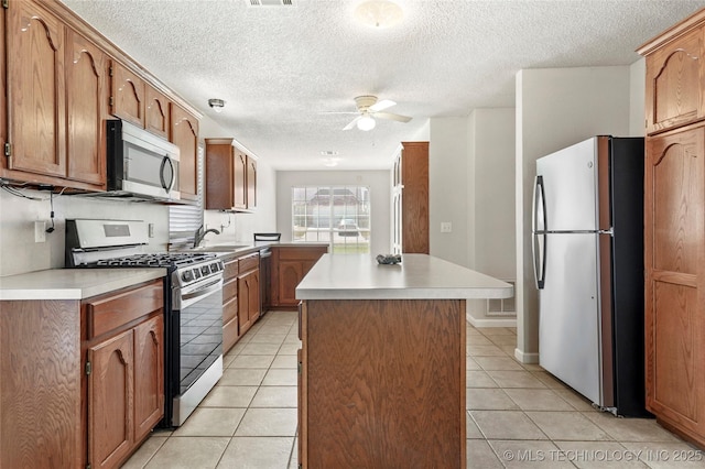 1309 N Willow Ave, Broken Arrow, OK 74012 - kitchen with stainless steel appliances, a ceiling fan, a sink, light tile patterned floors, and light countertops