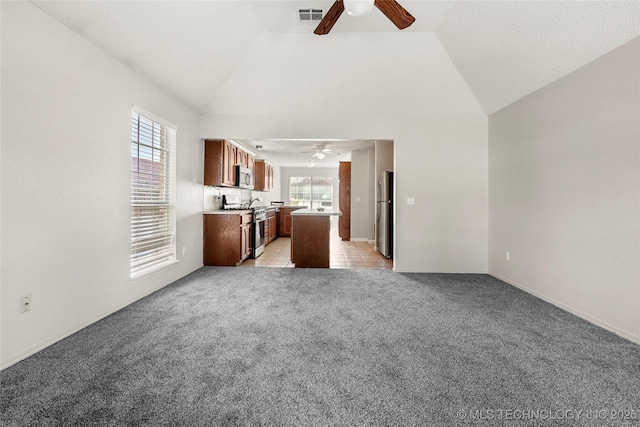 1309 N Willow Ave, Broken Arrow, OK 74012 - unfurnished living room featuring a ceiling fan, light carpet, vaulted ceiling, baseboards, and light tile patterned floors