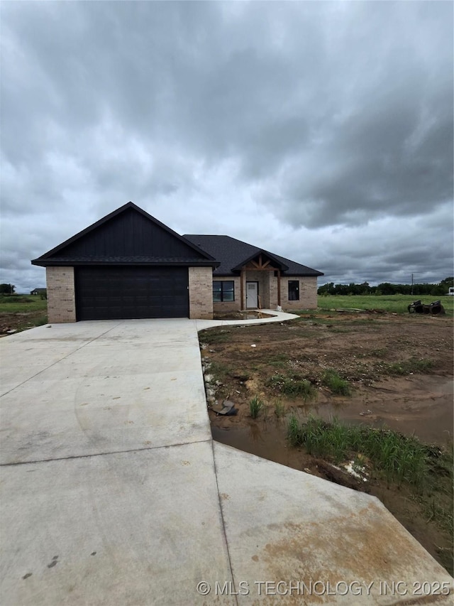 139 Grace Ln, Calera, OK 74730 - view of front of property featuring a garage, driveway, brick siding, and board and batten siding