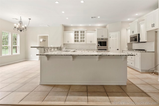 13041 E 67th St, Broken Arrow, OK 74012 - kitchen with stainless steel appliances, backsplash, a sink, light tile patterned flooring, and a breakfast bar