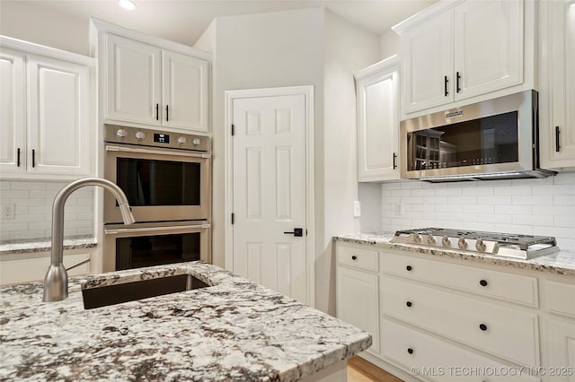 13041 E 67th St, Broken Arrow, OK 74012 - kitchen featuring stainless steel appliances, a sink, light stone countertops, tasteful backsplash, and recessed lighting