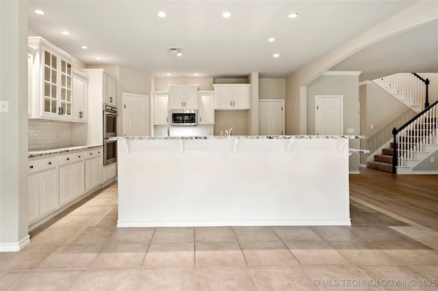 13041 E 67th St, Broken Arrow, OK 74012 - kitchen featuring appliances with stainless steel finishes, backsplash, recessed lighting, light stone countertops, and arched walkways