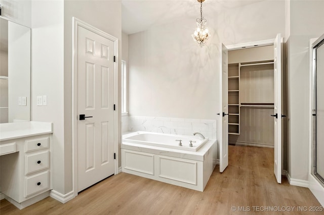 13041 E 67th St, Broken Arrow, OK 74012 - full bath featuring wood finished floors, a bath, a walk in closet, and a stall shower