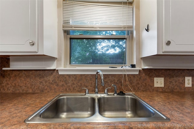 901 S Lions Ave, Broken Arrow, OK 74012 - kitchen view of a sink, dark countertops, white cabinetry, and tasteful backsplash