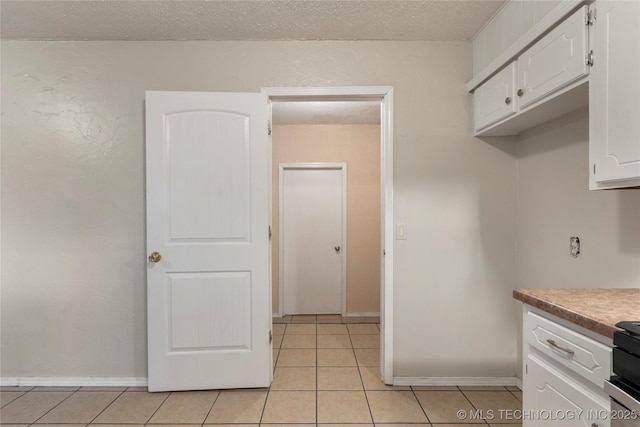 901 S Lions Ave, Broken Arrow, OK 74012 - kitchen with white cabinetry, light tile patterned floors, and a textured ceiling