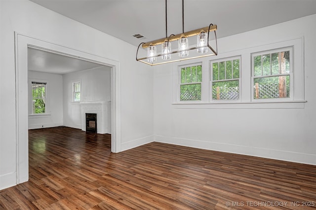 316 K St SW, Ardmore, OK 73401 - unfurnished dining area featuring a chandelier, dark wood finished floors, a brick fireplace, and baseboards