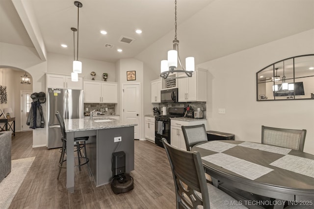 7506 E 87th Pl, Owasso, OK 74055 - dining area featuring a chandelier, arched walkways, dark wood-style floors, recessed lighting, and vaulted ceiling
