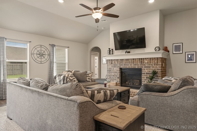 7506 E 87th Pl, Owasso, OK 74055 - living room with arched walkways, a ceiling fan, a brick fireplace, vaulted ceiling, and wood finished floors