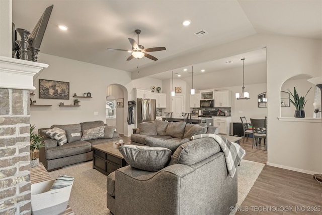 7506 E 87th Pl, Owasso, OK 74055 - living area featuring arched walkways, ceiling fan, vaulted ceiling, light wood-style floors, and recessed lighting