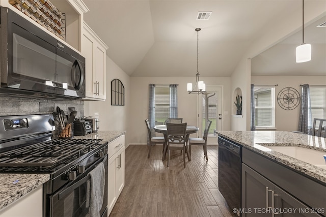 7506 E 87th Pl, Owasso, OK 74055 - kitchen with black appliances, backsplash, vaulted ceiling, white cabinets, and hanging light fixtures