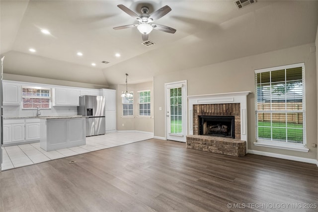 4309 W College St, Broken Arrow, OK 74012 - unfurnished living room featuring vaulted ceiling, a ceiling fan, light wood-type flooring, a brick fireplace, and baseboards