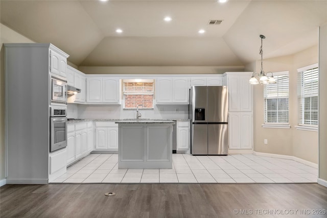 4309 W College St, Broken Arrow, OK 74012 - kitchen with stainless steel appliances, vaulted ceiling, light wood finished floors, white cabinetry, and a chandelier