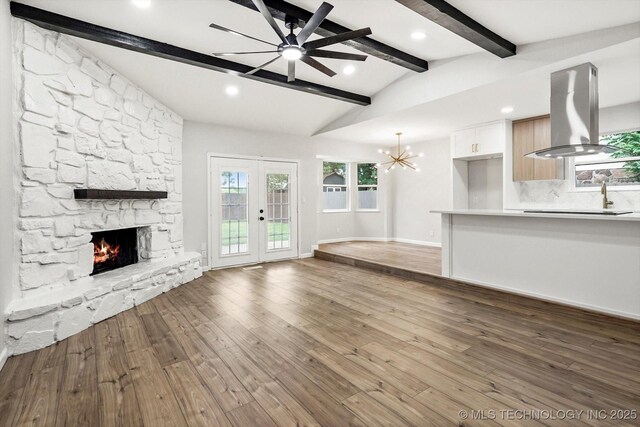 10128 E 34th St, Tulsa, OK 74146 - unfurnished living room with a fireplace, ceiling fan, baseboards, wood finished floors, and a chandelier