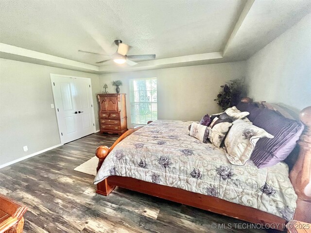 175 Johnson Rd, Broken Bow, OK 74728 - bedroom featuring wood finished floors, a tray ceiling, ceiling fan, baseboards, and a textured ceiling