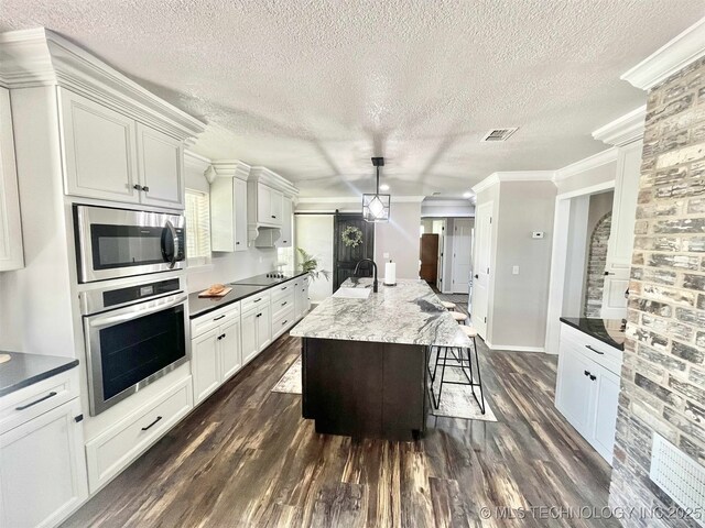 175 Johnson Rd, Broken Bow, OK 74728 - kitchen with appliances with stainless steel finishes, dark wood-style flooring, a textured ceiling, crown molding, and a kitchen bar
