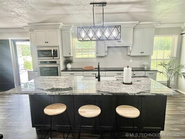 175 Johnson Rd, Broken Bow, OK 74728 - kitchen with stainless steel appliances, wood finished floors, a textured ceiling, crown molding, and decorative light fixtures